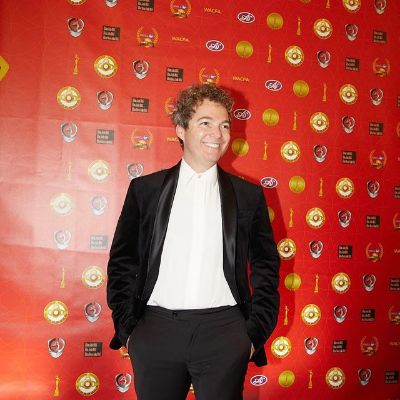 He is wearing a black suit and a white shirt.